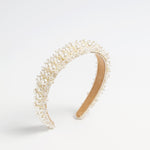 Beaded pearl headband with layered pearl detailing on a neutral background