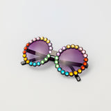 Carousel Color sunglasses with round black frames and rainbow rhinestone trim, shown from front on white background