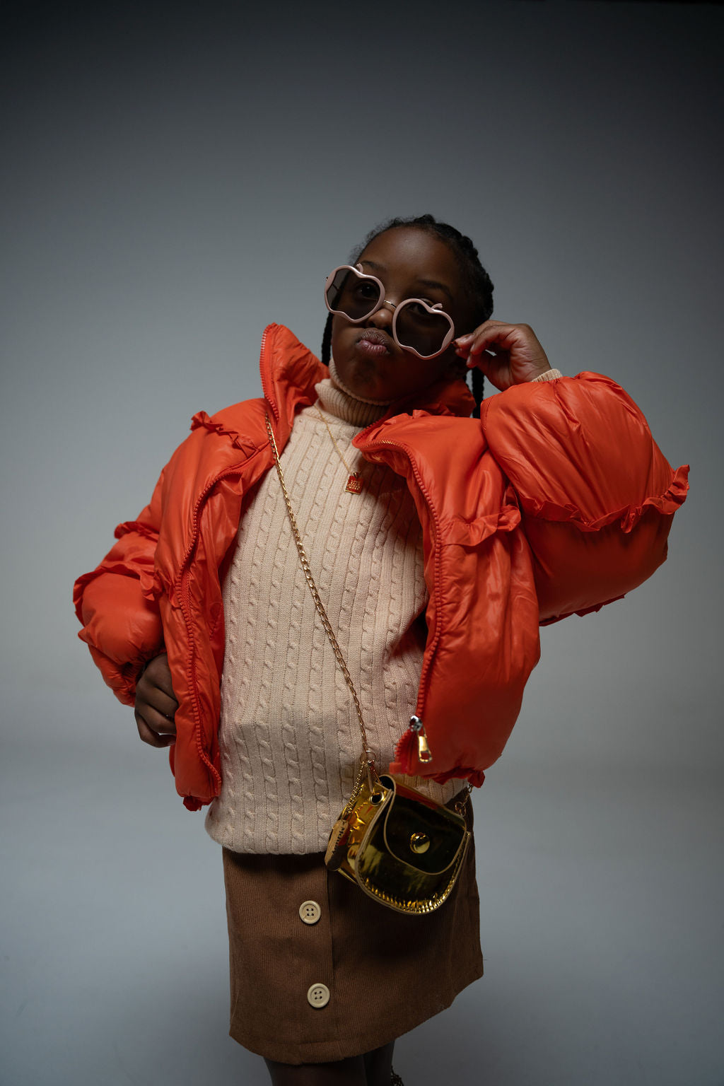 Girl posing in puffer jacket wearing Gala Princess sunglasses in pink with apple-shaped frames