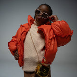 Girl posing in puffer jacket wearing Gala Princess sunglasses in pink with apple-shaped frames