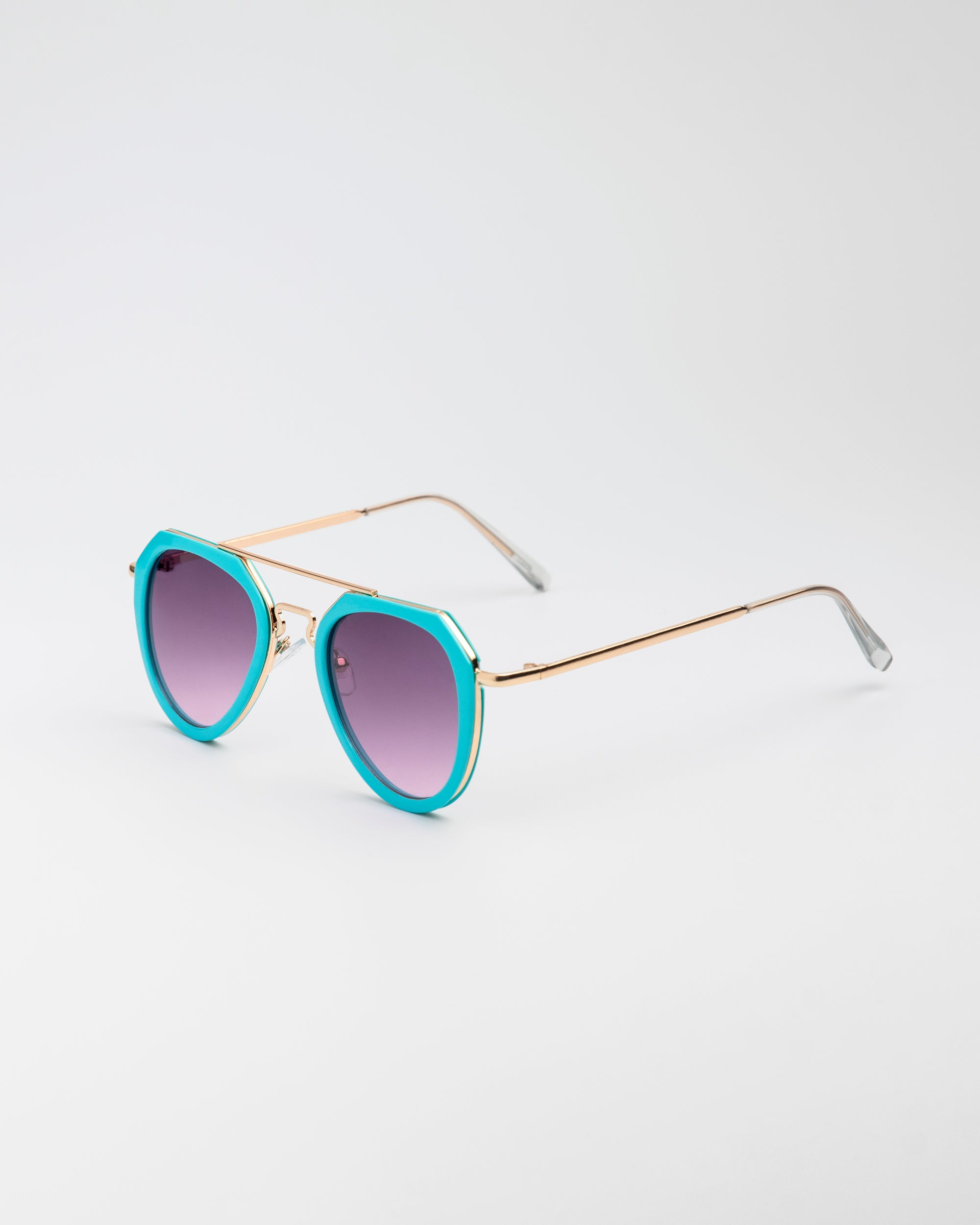 Jet Set sunglasses with turquoise and gold aviator-style frames and cool purple tinted lenses on white background