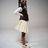 Girl in side profile pose wearing Little Miss Beary Glasses, styled with cream pleated skirt and brown vest