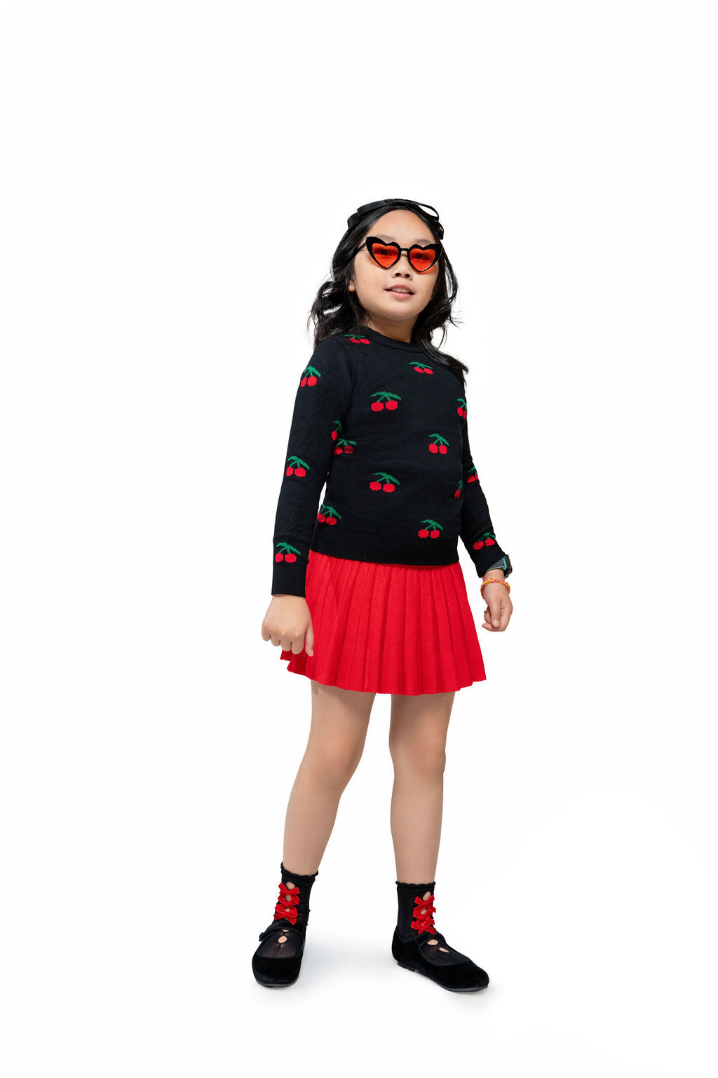 The orange lensed, black heart shaped sunglasses worn by a model in a red and black cherry themed outfit