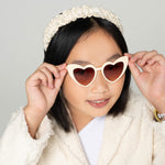 Full face of smiling child in princess heart sunglasses and sparkly headband