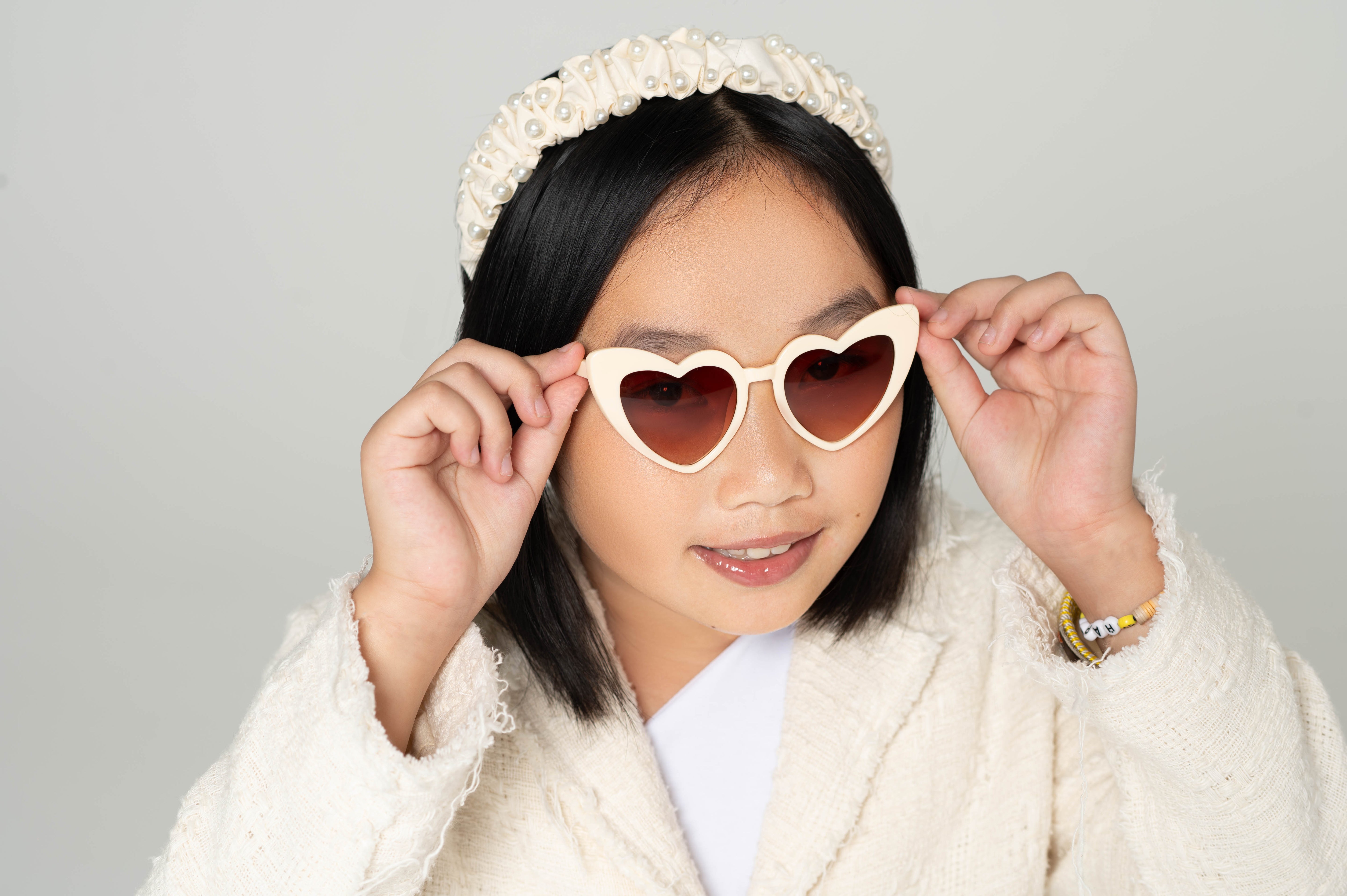 Full face of smiling child in princess heart sunglasses and sparkly headband